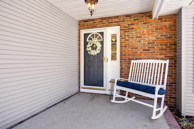 doorway to property featuring brick siding and a porch