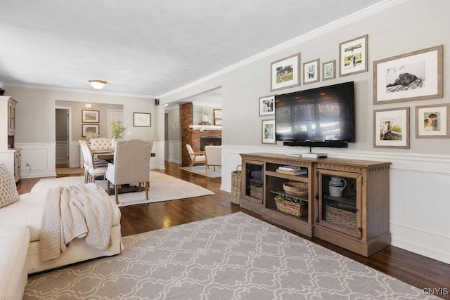 living room with wainscoting, wood finished floors, crown molding, and a decorative wall