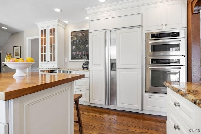 kitchen featuring recessed lighting, white cabinets, glass insert cabinets, wood counters, and double oven