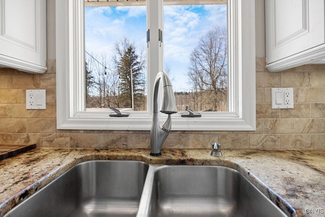 room details with a sink, decorative backsplash, and light stone counters