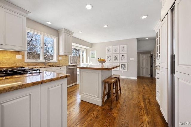 kitchen with dishwasher, decorative backsplash, white cabinetry, and a breakfast bar