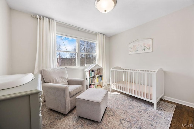 bedroom featuring a nursery area, wood finished floors, and baseboards