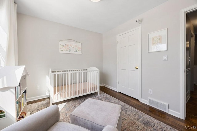 bedroom with wood finished floors, visible vents, and baseboards