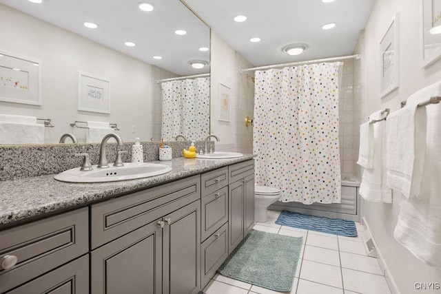 full bath with a sink, toilet, double vanity, and tile patterned flooring