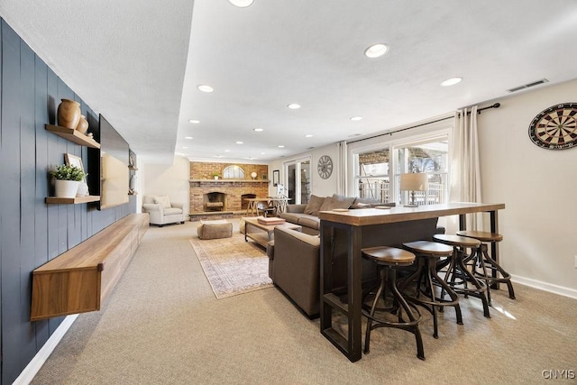 living room with visible vents, recessed lighting, a fireplace, baseboards, and light colored carpet