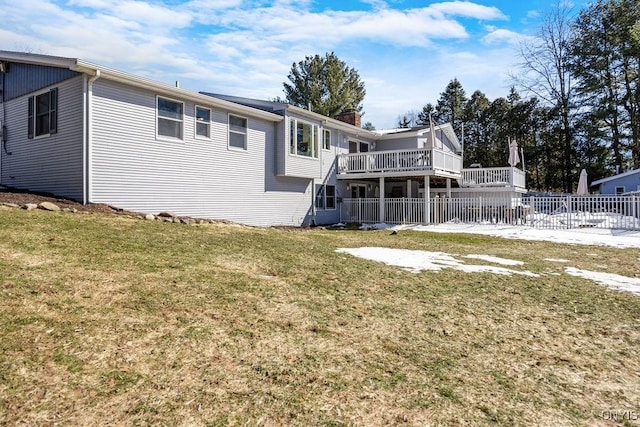 rear view of house with a yard, a wooden deck, a chimney, and fence