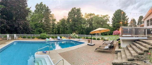 pool at dusk with a patio area, a fenced in pool, a diving board, and fence