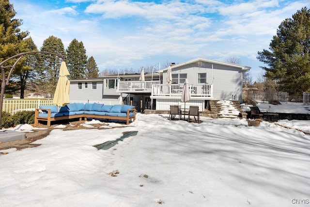 snow covered property featuring a wooden deck, outdoor lounge area, stairs, and fence