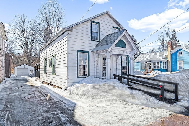 view of front of property with a garage, an outbuilding, and roof with shingles