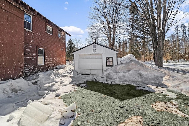 snow covered property with a garage and an outbuilding