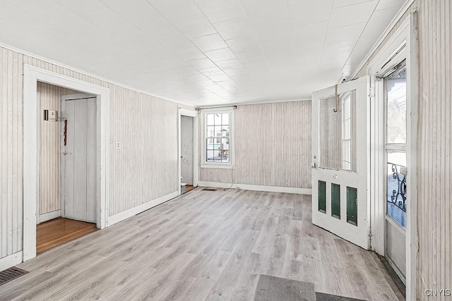 unfurnished living room featuring visible vents, wood finished floors, baseboards, and a wealth of natural light