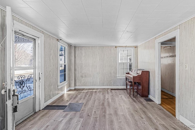 foyer featuring wooden walls, baseboards, and wood finished floors