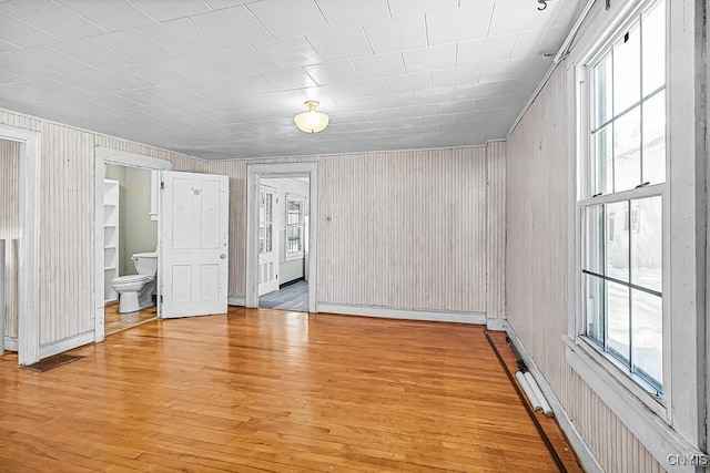 unfurnished bedroom featuring multiple windows, ensuite bathroom, and light wood-type flooring