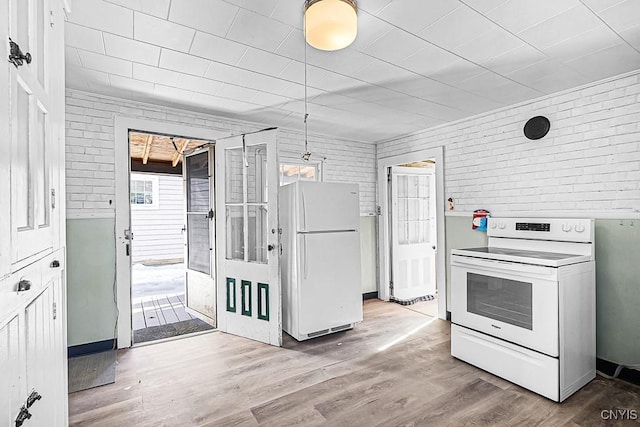 kitchen featuring white appliances, wood finished floors, and brick wall