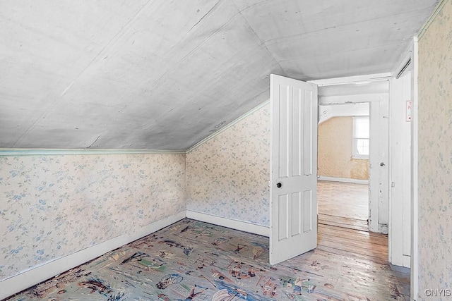 bonus room featuring baseboards, wallpapered walls, lofted ceiling, and hardwood / wood-style flooring