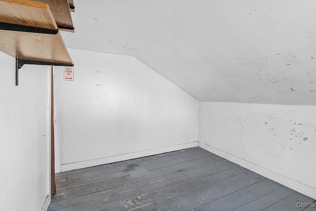 additional living space featuring vaulted ceiling and dark wood-style floors