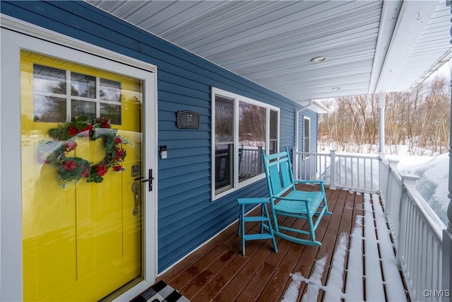 snow covered deck featuring a porch