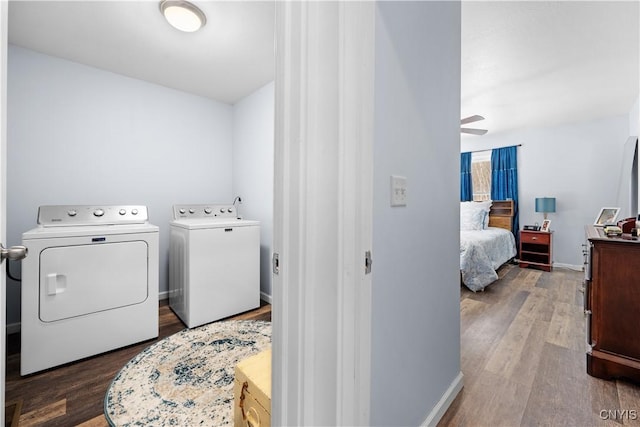 clothes washing area with baseboards, independent washer and dryer, wood finished floors, and laundry area