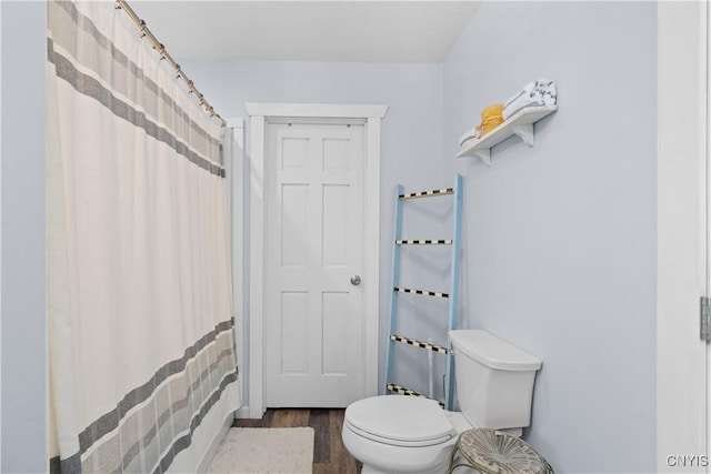 bathroom with curtained shower, toilet, and wood finished floors