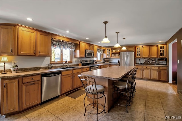 kitchen with a breakfast bar area, a sink, appliances with stainless steel finishes, brown cabinets, and a center island