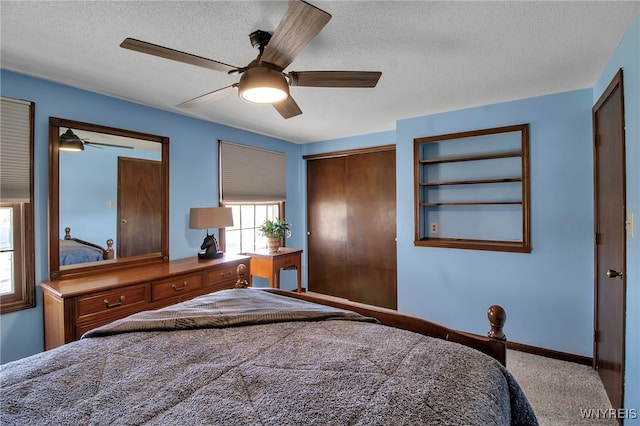 carpeted bedroom featuring a closet, baseboards, a textured ceiling, and ceiling fan