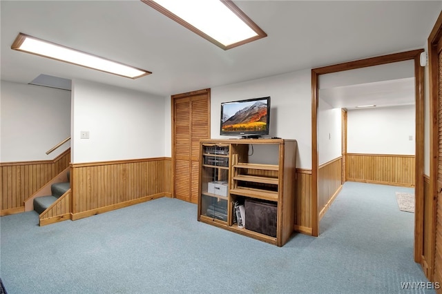 interior space with a wainscoted wall, wooden walls, carpet flooring, and stairway