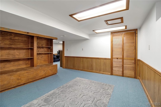 finished basement with wooden walls, carpet floors, and wainscoting