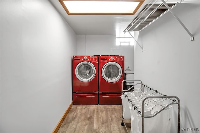 clothes washing area with laundry area, washing machine and dryer, baseboards, and wood finished floors