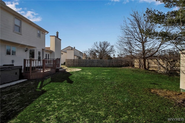 view of yard with a wooden deck, a fenced backyard, and a hot tub