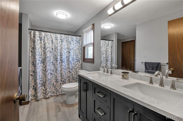 full bath with a sink, toilet, wood finished floors, and double vanity