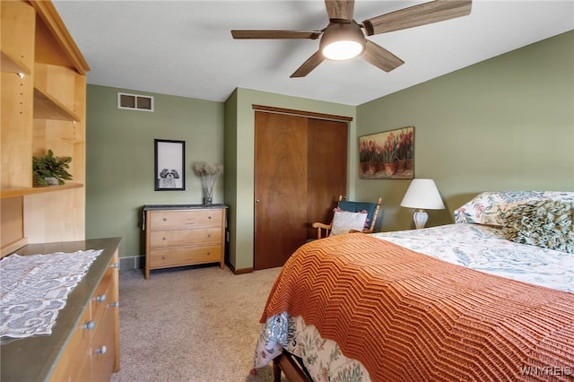 bedroom featuring visible vents, a closet, baseboards, light colored carpet, and ceiling fan