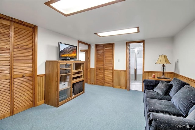 living room featuring carpet floors, wooden walls, and wainscoting