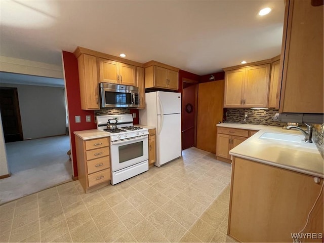 kitchen featuring a sink, backsplash, white appliances, light countertops, and light floors