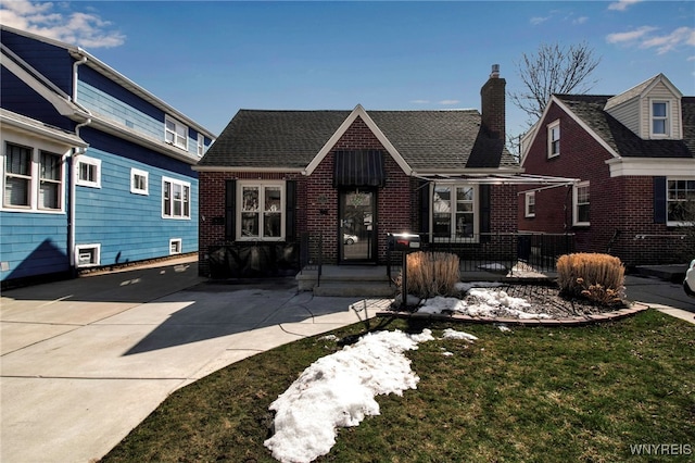 view of front of property featuring brick siding, a chimney, and a shingled roof