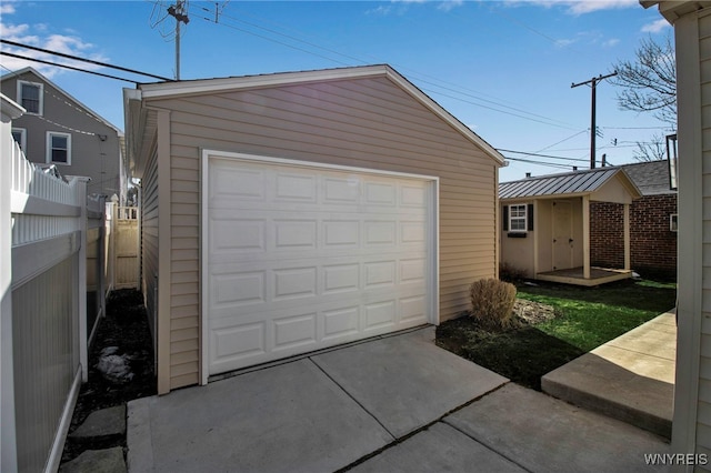 detached garage featuring driveway and fence