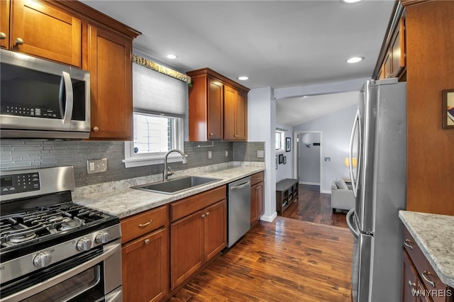 kitchen with decorative backsplash, brown cabinets, dark wood-style floors, stainless steel appliances, and a sink