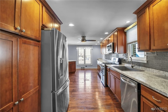 kitchen with a sink, ceiling fan, dark wood-type flooring, stainless steel appliances, and backsplash