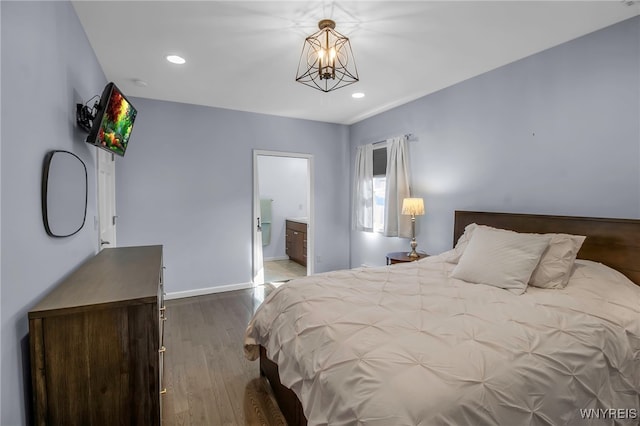 bedroom featuring baseboards, recessed lighting, wood finished floors, a notable chandelier, and ensuite bath