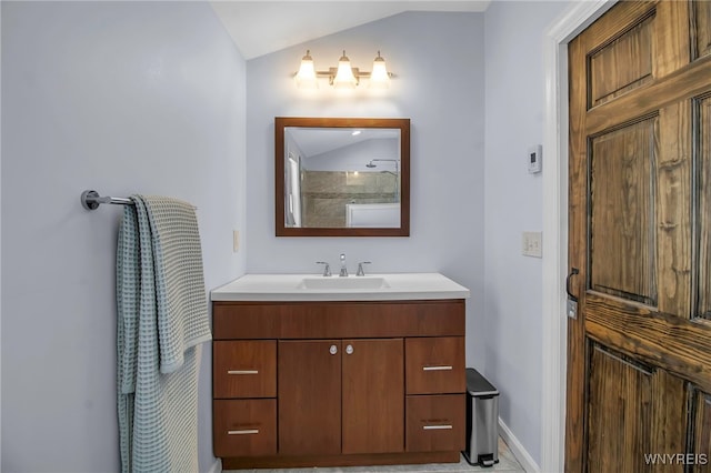 bathroom with baseboards, vanity, and vaulted ceiling