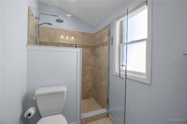 bathroom featuring lofted ceiling, toilet, and a tile shower