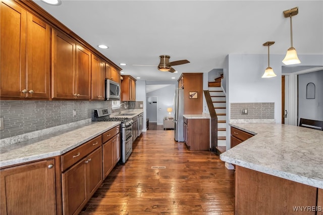 kitchen featuring dark wood-type flooring, ceiling fan, brown cabinets, appliances with stainless steel finishes, and a sink