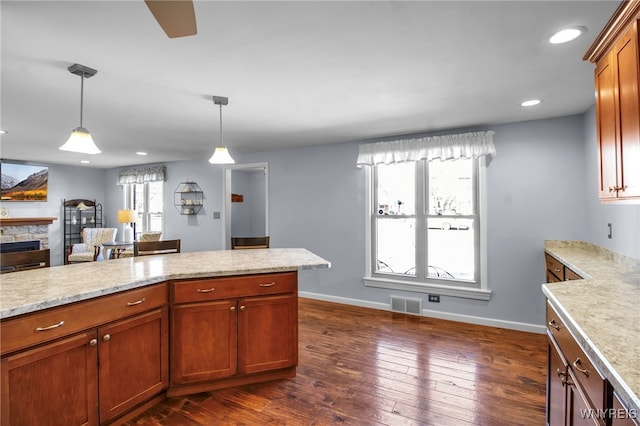 kitchen with visible vents, baseboards, decorative light fixtures, a fireplace, and dark wood-style flooring