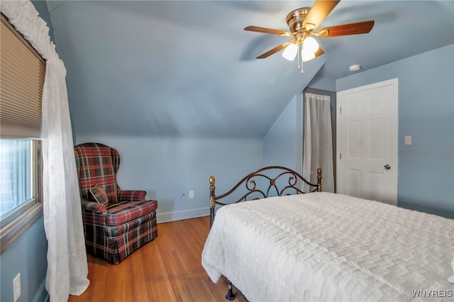 bedroom featuring a ceiling fan, lofted ceiling, baseboards, and wood finished floors