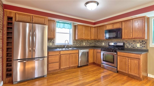 kitchen featuring dark countertops, light wood-type flooring, appliances with stainless steel finishes, and a sink