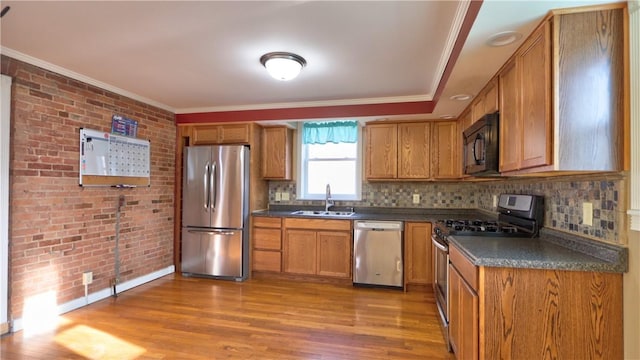 kitchen featuring a sink, dark countertops, appliances with stainless steel finishes, and brick wall