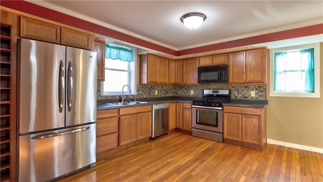 kitchen with dark countertops, brown cabinets, appliances with stainless steel finishes, and a sink