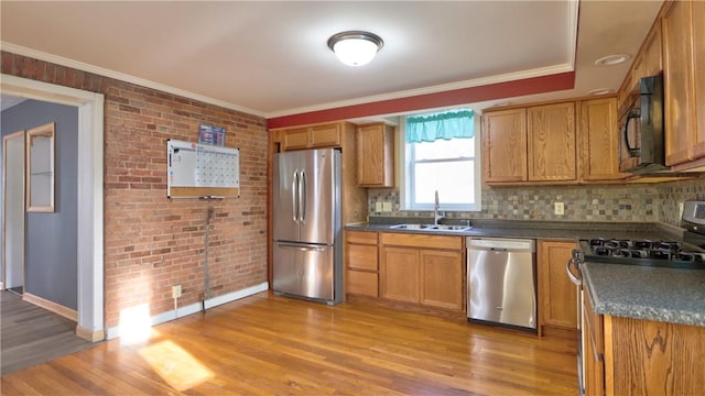 kitchen featuring dark countertops, crown molding, appliances with stainless steel finishes, and a sink