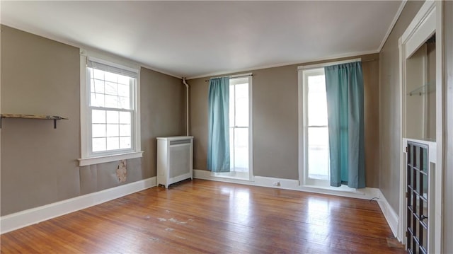 empty room with radiator heating unit, wood finished floors, and baseboards