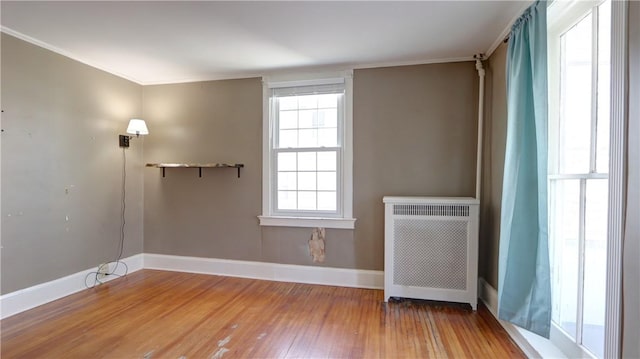 unfurnished room with baseboards, wood-type flooring, and radiator