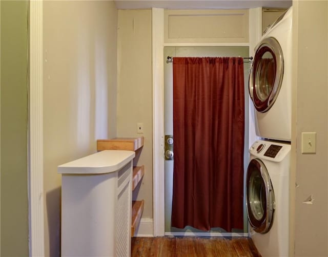 clothes washing area featuring laundry area, stacked washer / dryer, and wood finished floors